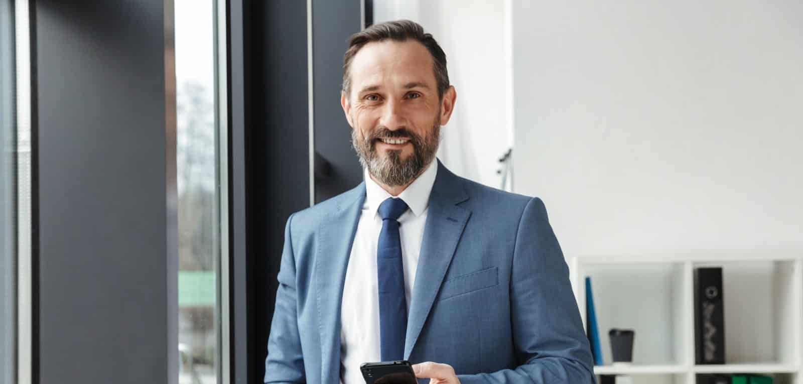 photo-of-bearded-smiling-businessman-in-formal-sui-LXQESHV